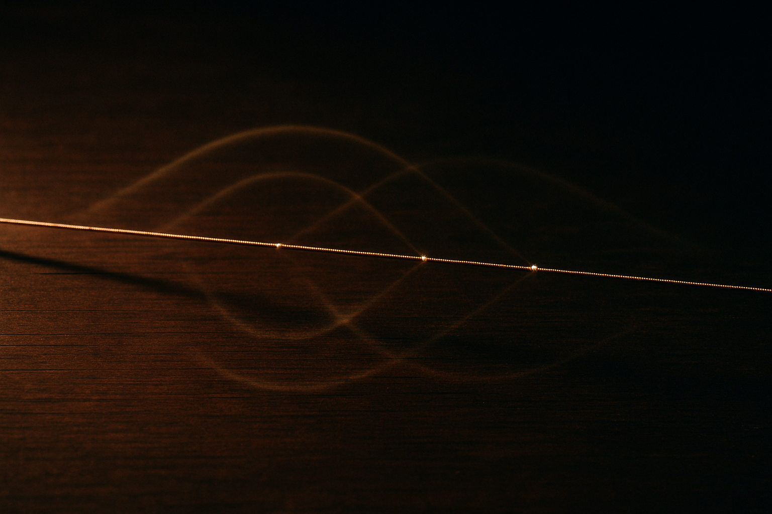 A single taut brass string stretched across a dark wooden soundboard, vibrating so that its blurred full-length arc is overlaid by fainter ghost waves